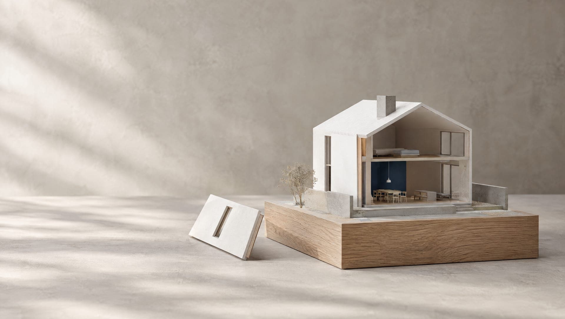 Weisses Architekturmodell eines Einfamilienhauses auf einem Sockel aus Eiche; eine Wandplatte fehlt am Modell und liegt daneben